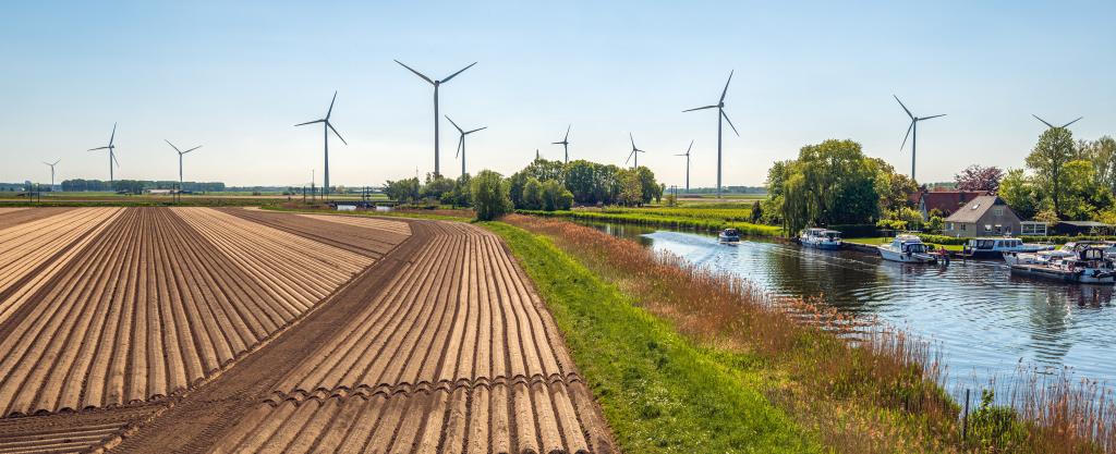 Aardappelakker en jachthaven in Hoeven, naast rivier De Mark, met op de achtergrond windmolens