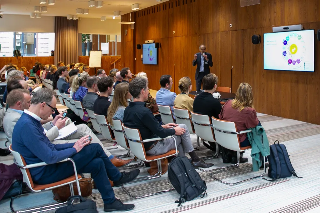 Seminarzaal waar Bert Tieben een publiek toespreekt